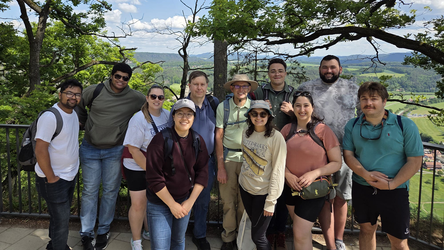Group of students and faculty at overlook view with trees and mountains behind them.