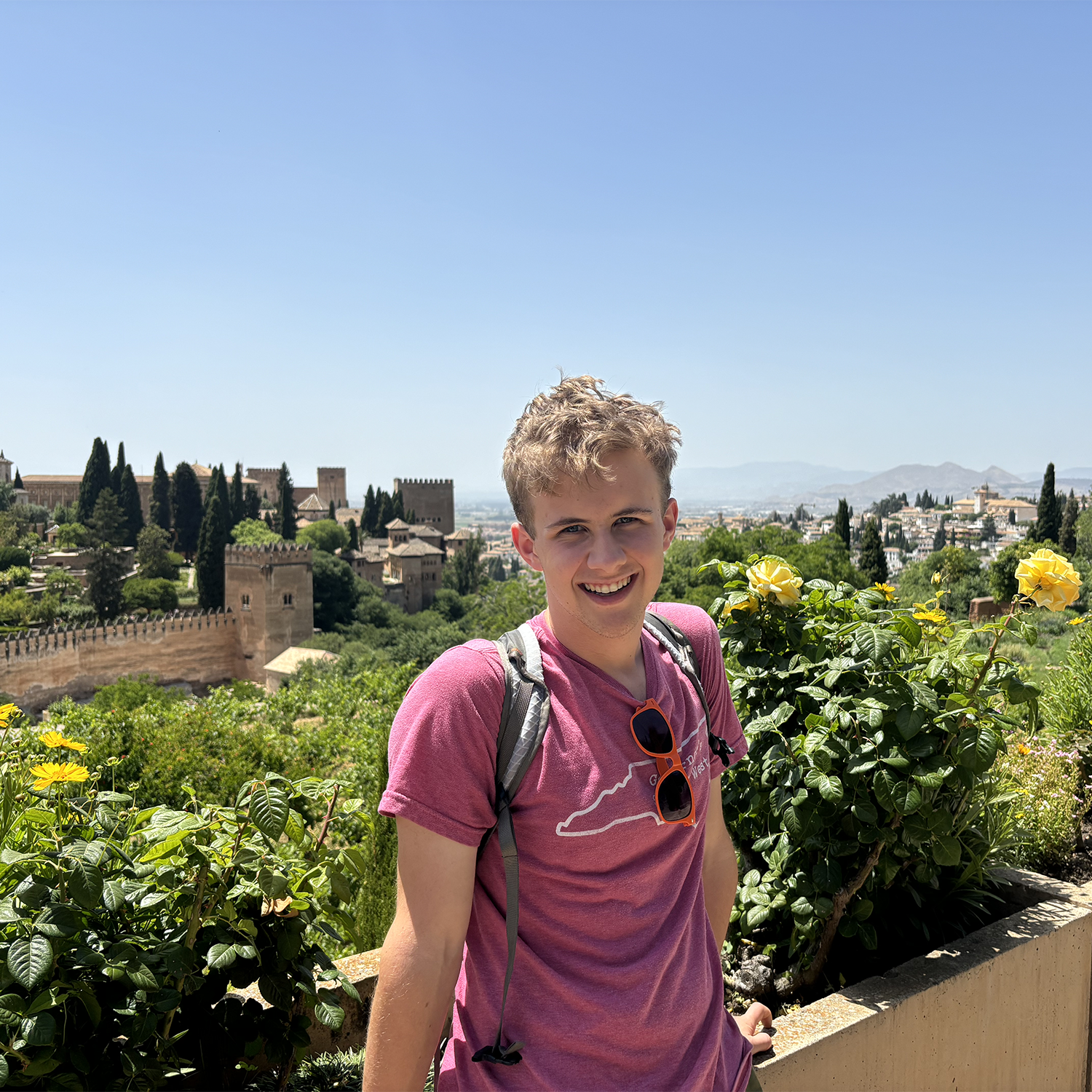 blonde college aged male perched atop a castle in Spain